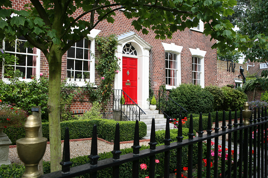 Nice brick home with decorative fence and red front door.