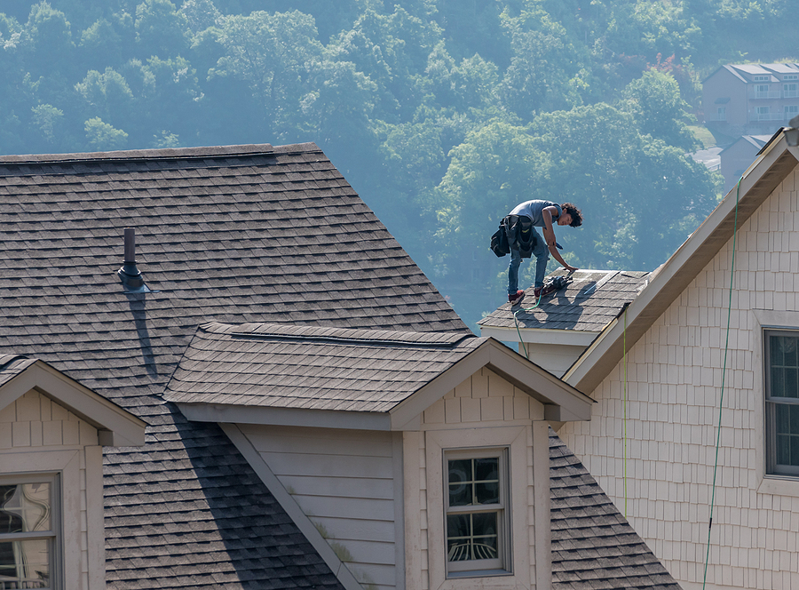 Roofer working on top of a residential roof.