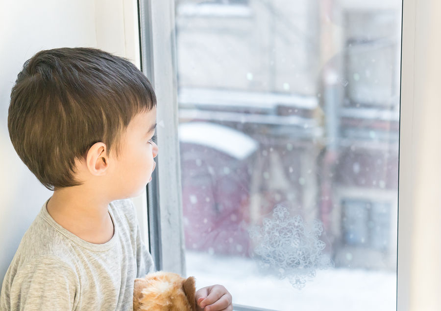 Small Boy Watching Snowy Weather Through Window
