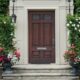 Solid dark wood front door of home surrounded by ivy and plants