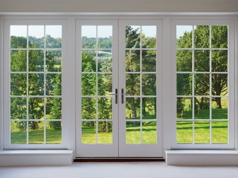Set of patio doors with white frame overlooking beautiful countryside garden