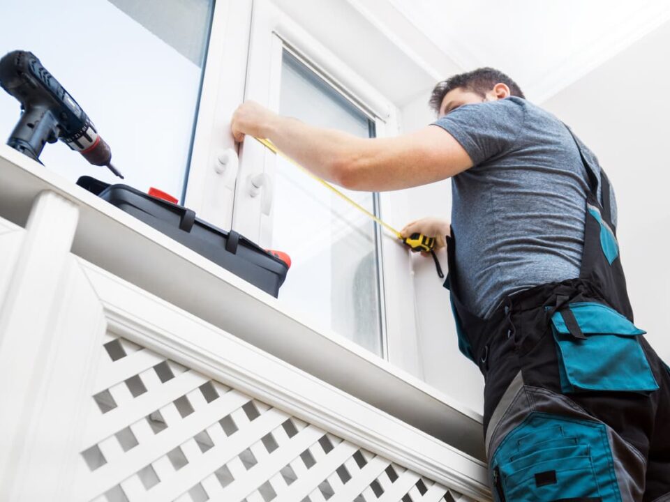 Worker measuring windows with tape